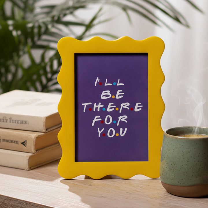 Yellow Scalloped Friend Quote A5 frame, placed on the table with some books and a cup of coffee. 